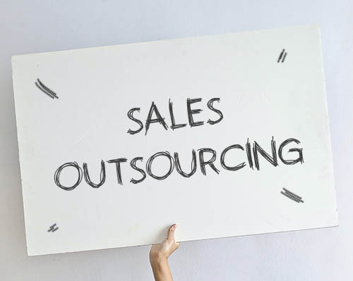 Person holding a Sign saying 'Sales outsourcing'